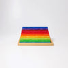 Grimm's Stepped Counting Blocks - Small (coming soon) are neatly arranged in a wooden tray, featuring rows of rectangular wooden blocks in gradient colors from green at the front to yellow, orange, red, and blue at the back on a white background.