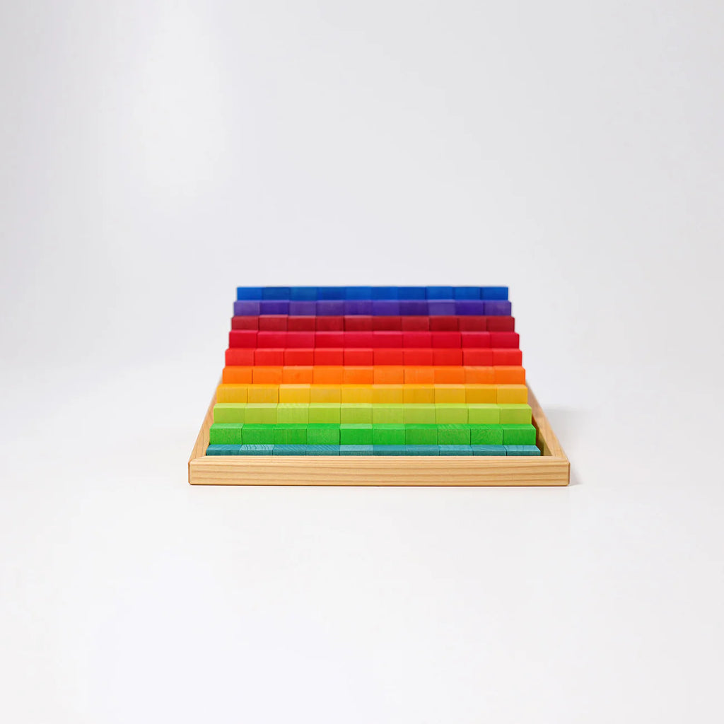 Grimm's Stepped Counting Blocks - Small (coming soon) are neatly arranged in a wooden tray, featuring rows of rectangular wooden blocks in gradient colors from green at the front to yellow, orange, red, and blue at the back on a white background.