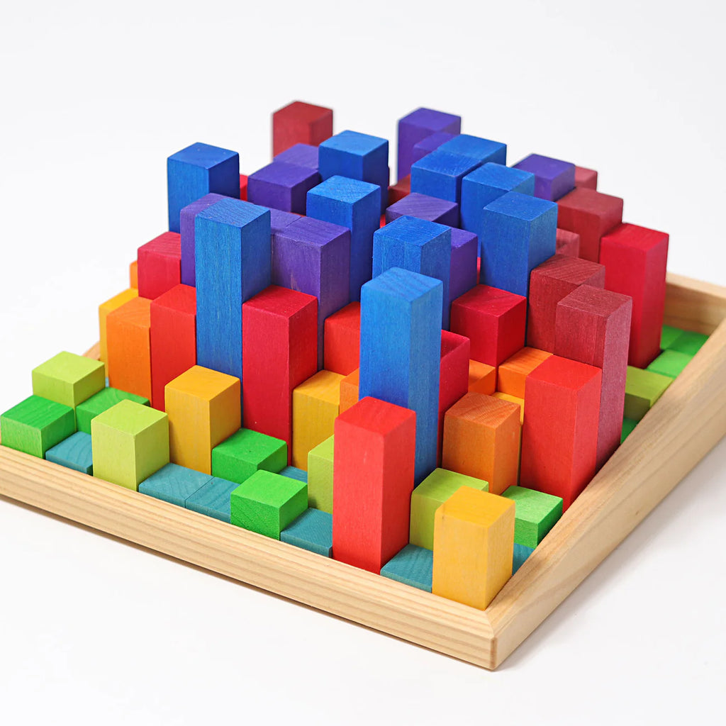Grimm's Stepped Counting Blocks - Small (coming soon): A wooden tray with non-toxic blocks in green, yellow, orange, red, blue, and purple, arranged by height in a grid that creates a vibrant cityscape effect.
