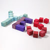 The Grimm's Large Mosaic Block Set, featuring non-toxic wooden blocks in blue, purple, and red, is arranged on a white background to form the letters "H," "C," and the number "15." The blue blocks create the 'H,' the purple blocks form the 'C,' and the red blocks represent "15," promoting fine motor skills through creative play.