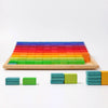 Grimm’s Stepped Counting Blocks - Large, featuring rainbow-colored building blocks arranged in a stepped wooden frame with several loose blocks stacked in the foreground.
