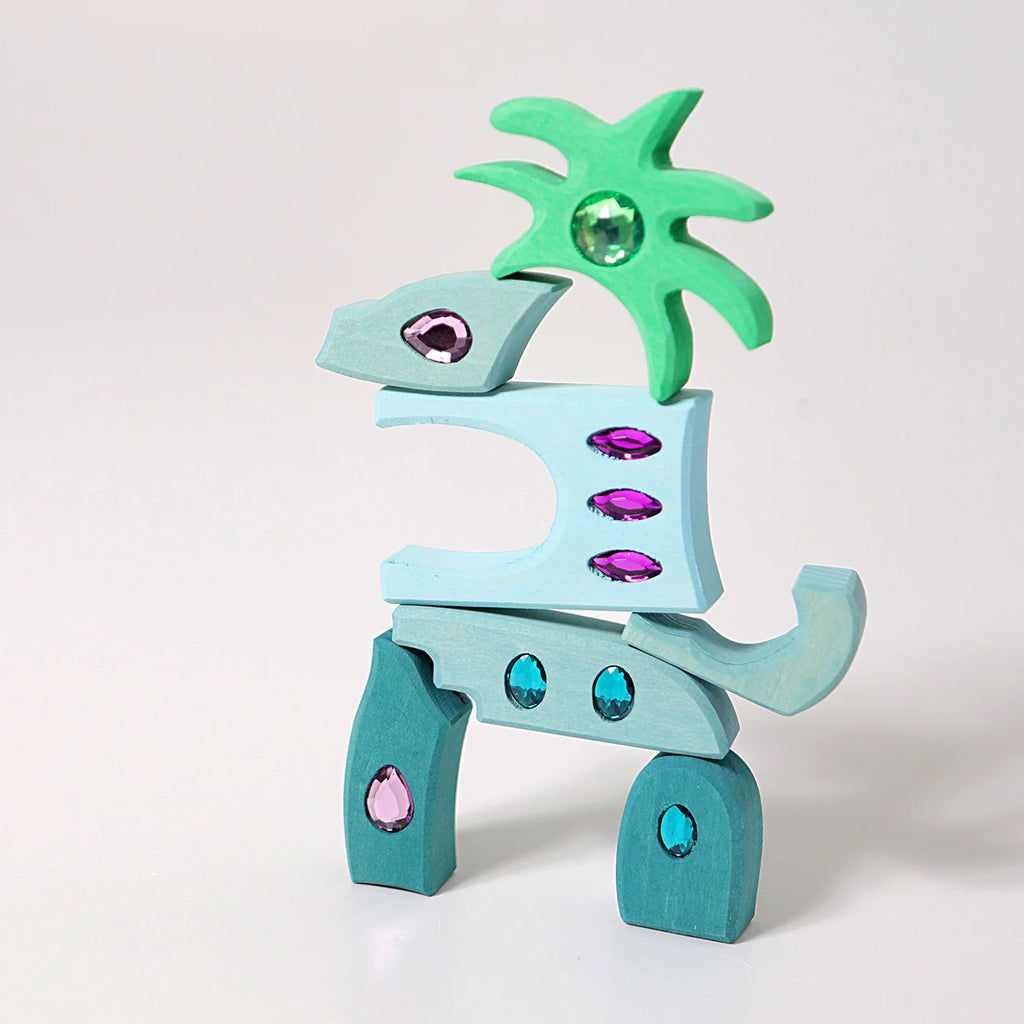 Grimm's Sparkling Mandala Orient, a whimsical wooden toy in blue and green with glitter stones, is upright against a plain white background. Ships in 1-2 weeks.