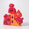 Grimm's Sparkling Mandala Orient features colorful, irregular wooden blocks in red, orange, and pink, adorned with large shiny red and purple gems for an imaginative building experience.