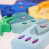 Grimm's Sparkling Mandala Orient (ships in 1-2 weeks) features painted wooden blocks with embedded glitter stones, arranged in a green-to-blue-to-yellow gradient for a vibrant, tactile display.