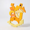 Grimm's Sparkling Mandala Orient, a set of colorful yellow and orange wooden blocks with glittering stones, is artistically stacked against a plain white background. Ships in 1-2 weeks.