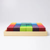 Grimm's Rainbow Mosaic Building Blocks features 25 vibrant wooden blocks arranged in a 5x5 grid within a sturdy wooden tray. The blocks come in an array of colors—including red, purple, blue, green, and yellow—and are neatly displayed on a white background. This set is ideal for fostering spatial thinking skills as children play and explore.