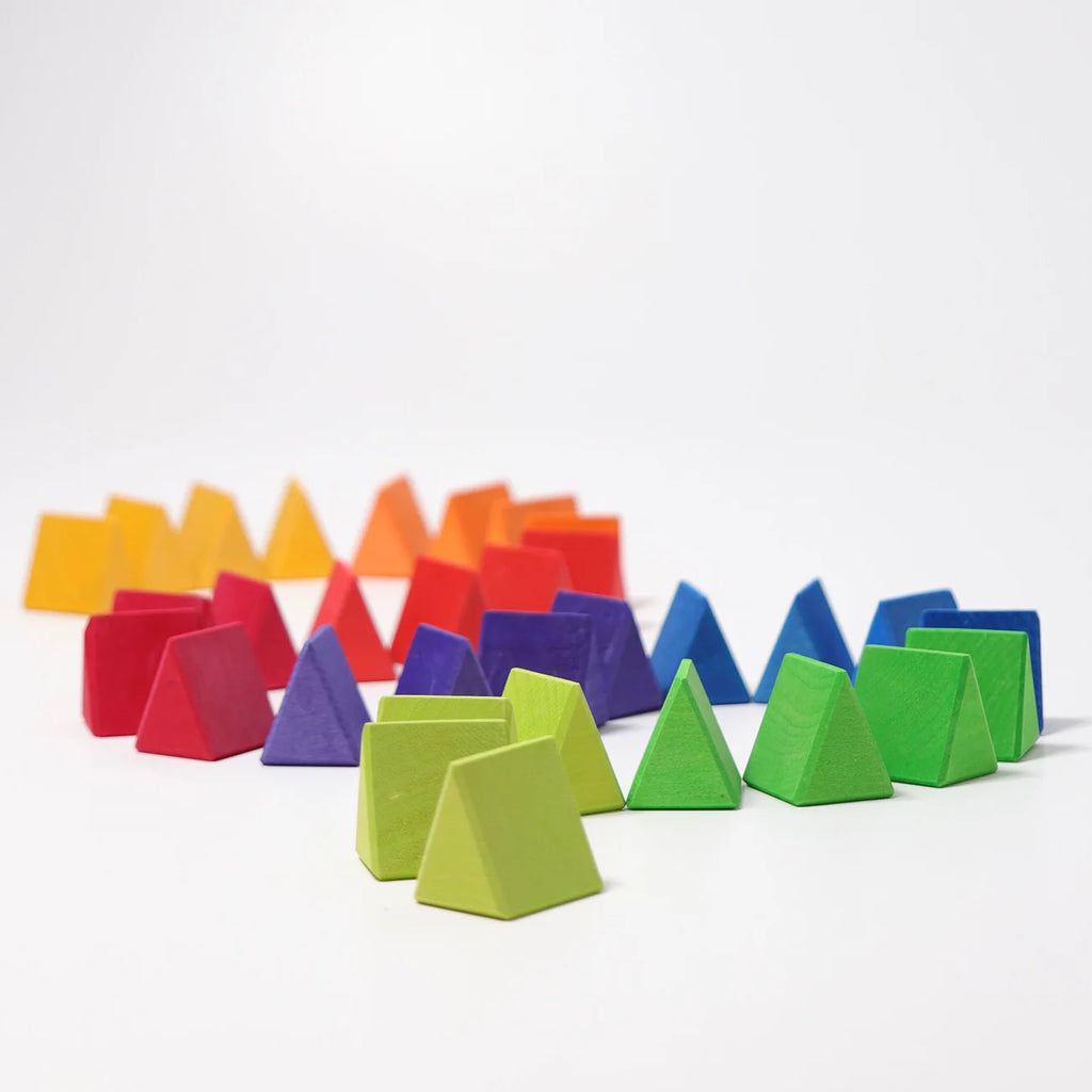 An array of Grimm’s Medium Octagon blocks (ships in 2-3 weeks) is artfully arranged in pyramid shapes, sorted by color gradient from green at the front and shifting to blue, purple, red, orange, and yellow toward the back against a plain white background. This vibrant display highlights the playful design and educational appeal of this geometric toy set.