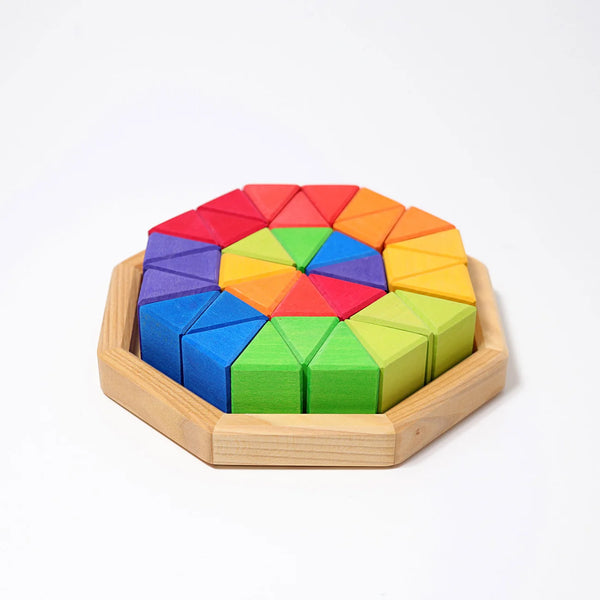 Grimm’s Medium Octagon (ships in 2-3 weeks) is a wooden puzzle set in an octagonal frame, featuring vibrant geometric building blocks—red, orange, yellow, green, blue, and purple triangles—arranged in a striking circular pattern.