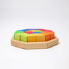 Grimm’s Medium Octagon (ships in 2-3 weeks) features a sturdy wooden octagonal tray filled with vibrant geometric building blocks arranged in a colorful rainbow pattern—including red, orange, yellow, green, blue, and purple sections. The set also includes triangle-shaped toy pieces, perfect for creative play and learning on a white background.