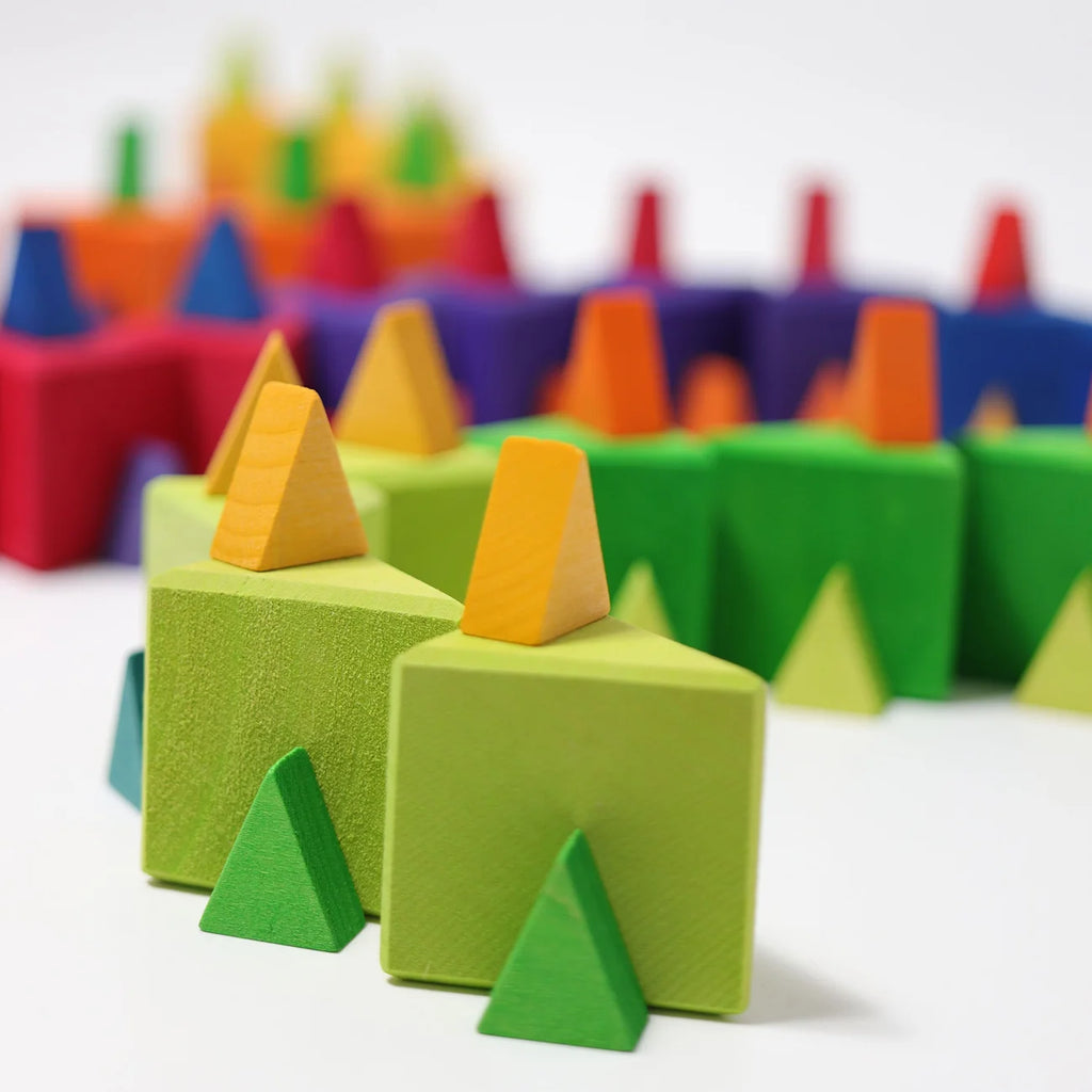 Grimm’s Medium Octagon (ships in 2-3 weeks) features colorful geometric wooden blocks in green, orange, yellow, red, purple, and blue tones. Arranged within wooden frames to resemble trees and houses, these vibrant shapes are beautifully displayed on a white surface.