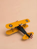 A small yellow handcrafted metal biplane model—Little Forest Animals: The Aviator—with U.S. Air Force insignia on both wings, viewed from above on a light peach background; perfect as unique barnstormer plane decor for any enthusiast’s collection.