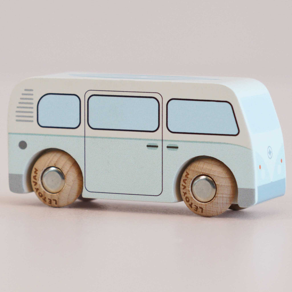 The No. 29 GT160 Daisy, a light blue and white vintage wooden campervan with simple painted details and wooden wheels, is showcased on a neutral background, evoking the charm of nostalgic play. Made in England.