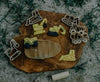 Construction vehicle-shaped cookies and matching Construction Cutter Set - Eco Playdough Tool cookie cutters are displayed on a wooden board atop grass. Accompanied by a small rolling pin and an oval "worksite" slab, this playful scene inspires creative sensory fun—making the Construction Cutter Set - Eco Playdough Tool ideal for imaginative little builders.