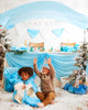 Two children delight in a winter-themed party, where one sits amid giant playsilks crafted from Sarah's Silk Giant Snow Playsilk. The other child raises their hands in excitement, embracing the creative possibilities of open-ended play surrounded by blue drapes, shimmering snowflakes, and small Christmas trees.