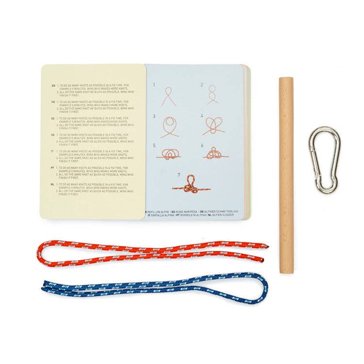 The Knot Game includes an open instruction booklet, a wooden dowel, a metal carabiner, and two ropes—one red and one blue—on a white surface for practicing essential and advanced knots.