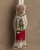 The Coral & Tusk Dog with Gifts Ornament features a pup in a festive sweater and red pants, holding a fishing rod with a fish, standing out against a neutral background.