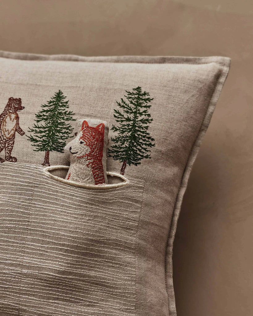 The Coral & Tusk Winter Foxes Pocket Pillow features embroidered trees, animals, and a plush fox in a pocket—a charming woodland accent perfect for adding playful decor to your child's nursery.