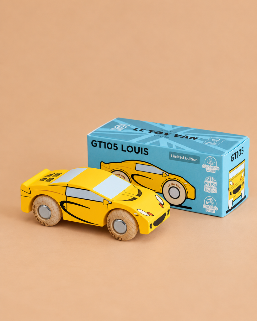 A yellow wooden sports car by Le Toy Van is displayed beside its blue box packaging labeled “No. 19 GT105 Louis | Made in England” and “Limited Edition” on a beige surface, capturing the charm of a classic toy car.