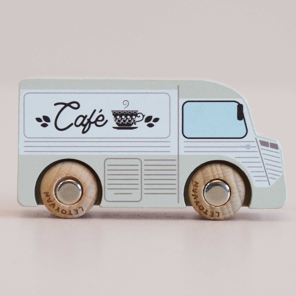 A charming small wooden coffee van, named No. 11 GT65 Coco and made in England, features a light blue finish with “Café” and a teacup graphic on the side. Complete with sturdy wooden wheels and playful, minimal detailing, it’s perfect for imaginative storytelling or as a thoughtful gift.