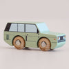 Introducing the No. 28 GT155 Rory | Made in England—a light green wooden 4x4 toy car featuring black and white window details and natural wood wheels, inspired by classic British design. Set against a plain light background, it’s perfect for little adventurers eager to embark on their next imaginative journey.