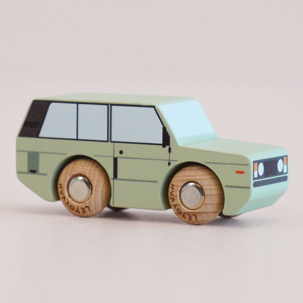 Introducing the No. 28 GT155 Rory | Made in England—a light green wooden 4x4 toy car featuring black and white window details and natural wood wheels, inspired by classic British design. Set against a plain light background, it’s perfect for little adventurers eager to embark on their next imaginative journey.