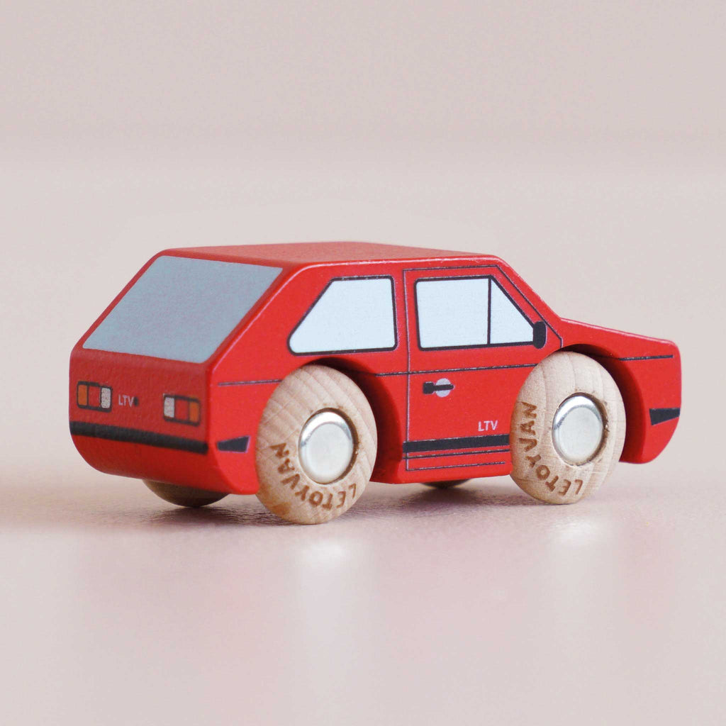 A No. 8 GT50 Gary | Made in England toy car, featuring a red wooden body with black details and four round, light-colored wheels, sits on a smooth, light surface, radiating vintage charm and retro cool.