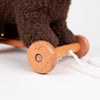 Close-up of Pull-Along Raoul by Egmont Toys, a delightful wooden pull-along toy with two wheels, featuring soft brown plush material on top and a white string for pulling, all displayed against a plain white background.