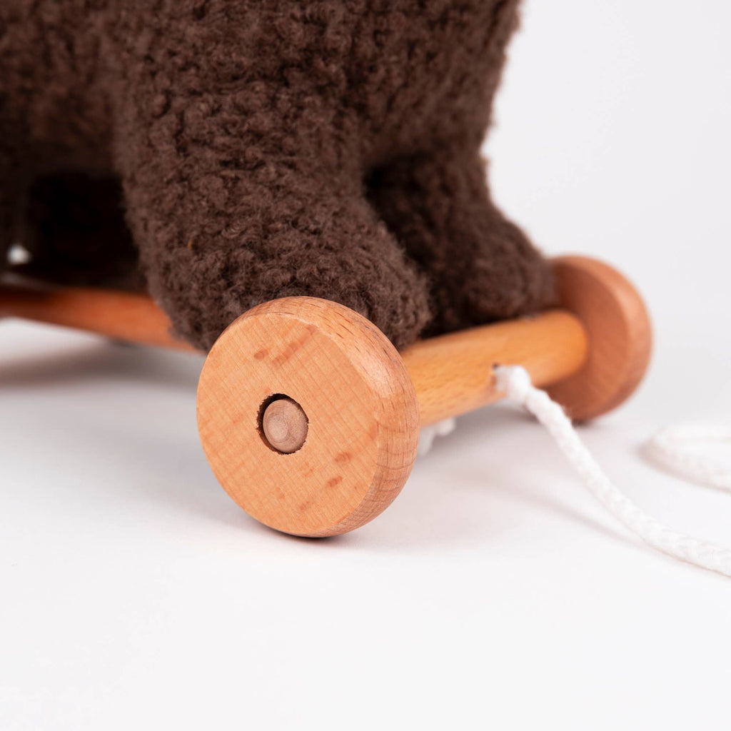 Close-up of Pull-Along Raoul by Egmont Toys, a delightful wooden pull-along toy with two wheels, featuring soft brown plush material on top and a white string for pulling, all displayed against a plain white background.