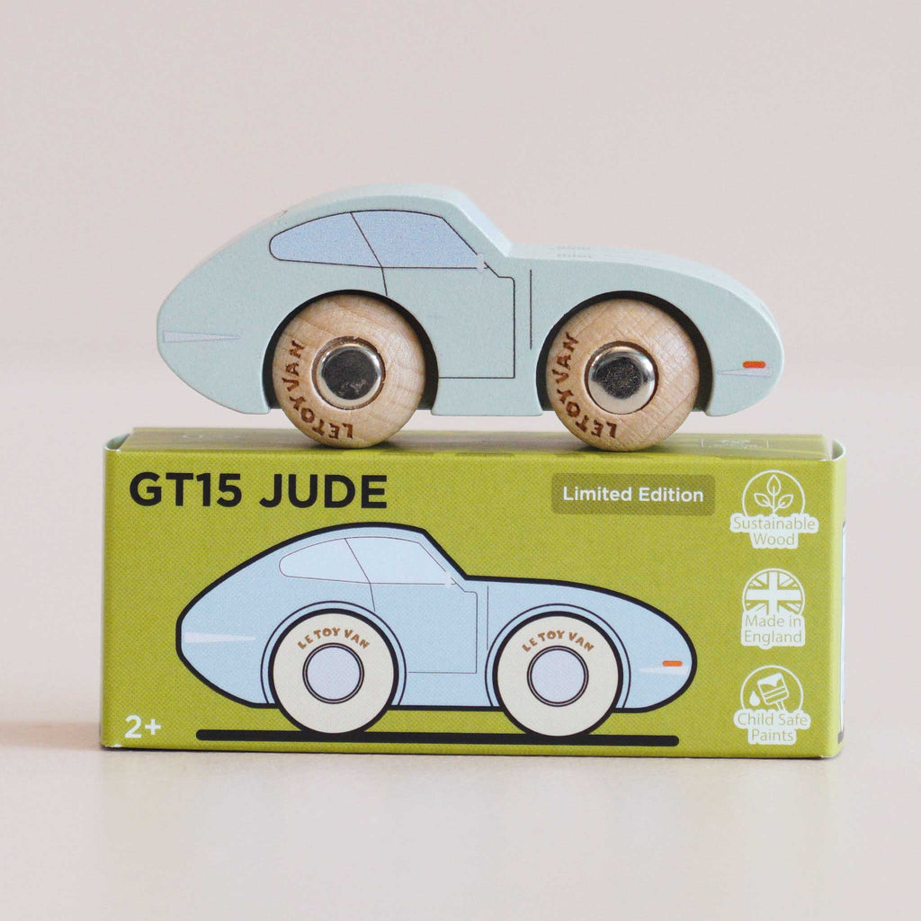 A light blue vintage wooden car, the No. 2 GT15 Jude made in England, sits atop a green box labeled “GT15 JUDE.” The box showcases a car illustration and icons highlighting sustainable wood, child-safe paints, and its English craftsmanship—making it a charming gift for kids.