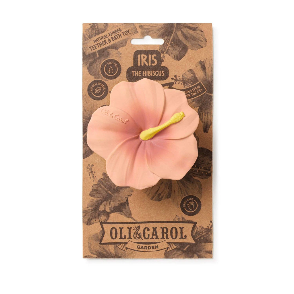 Iris the Hibiscus Teething Toy by OLI & CAROL Garden is a pink, hibiscus-shaped natural rubber teether and bath toy with a yellow stamen, displayed on brown botanical-themed packaging labeled "IRIS THE HIBISCUS.