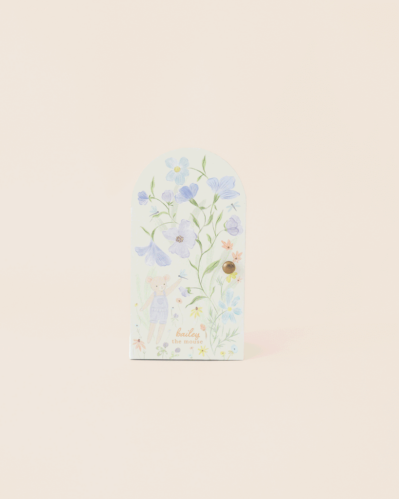 The Cuddle + Kind Tiny Bailey the Mouse card is handmade in Peru, featuring soft pastel bunny and floral illustrations in blue, purple, and yellow hues with “healing & good vibes” on the front.