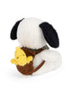 A Plush Peanuts Snoopy with black ears and a fluffy white body sits facing away, wearing a brown backpack that holds Woodstock, the small yellow plush bear.