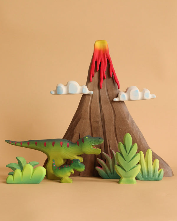 The Bumbu Prehistoric Set features toy dinosaurs and green plants before a toy volcano with red lava and two white clouds, all displayed against a beige background.