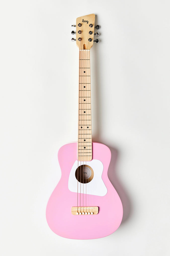 A pink Loog Pro Vi Acoustic Guitar Ages 9+ (ships in approximately one week) with a light wooden neck and fretboard. The acoustic guitar features a white pickguard and six strings, with metal tuning pegs on the headstock. Made from real wood, it stands vertically against a plain white background. Free lessons are included to get you started!