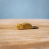 The Bumbu Handmade Wooden Baby Beaver, an eco-friendly Montessori toy, is displayed on a light wooden surface against a blurred blue background.