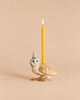 A handcrafted Barn Owl Cake Topper, featuring a ceramic owl wearing a blue party hat and holding a lit yellow candle on its back, is showcased against a plain beige background.