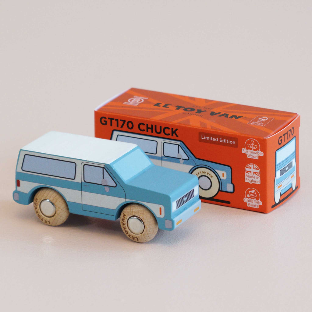 A wooden SUV toy car in blue and white sits next to its vibrant orange box labeled “No. 31 GT170 Chuck | Made in England,” adorned with illustrations of the car, various logos, and hints of off-road adventures for imaginative play.