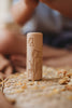 The Flower Roller - Eco Pattern Playdough Roller, featuring engraved tulip and butterfly designs on a wooden cylinder, stands upright on a woven mat surrounded by small dried petals—a perfect eco-friendly tool for sensory play.