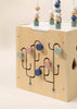 The Wooden Activity Cube features colorful knobs, curved tracks, and bead mazes. Designed in soft blue, green, pink, and beige tones, this toddler toy helps develop fine motor skills through engaging play.