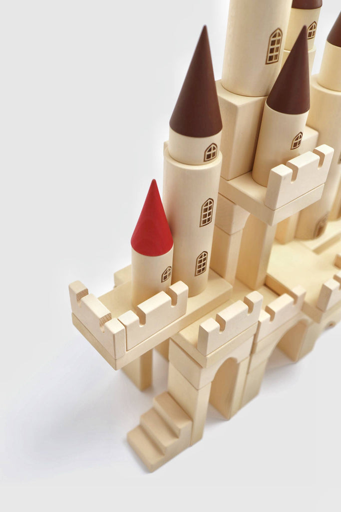 The Great Kingdom Building Set features cylindrical towers, cone-shaped roofs, and small windows. It includes brown and red rooftops with miniature battlements and stairs. Crafted with non-toxic paint and smooth edges, it ensures safe play against a plain background.