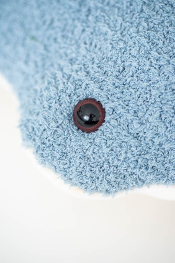 Close-up of a Light Blue Stingray with a single shiny black button. The texture of the fabric is soft and raised, resembling that of a plush toy or a cozy blanket.