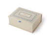 A closed, rectangular Delphine Large Embroidered Keepsake Box in cream, featuring decorative multicolored border patterns on the lid, a small blue ribbon pull tab on the front, and the word “Biscuits” written in the center.