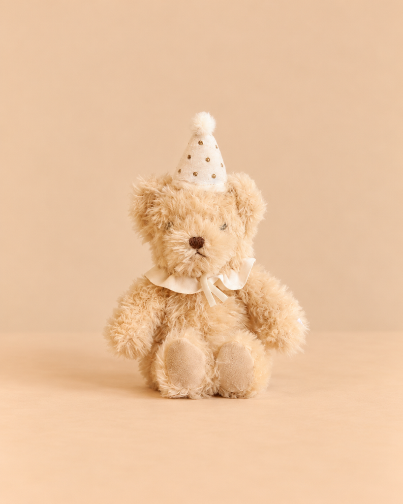 Snuggle Bunnies - Birthday Arthur - Ivory is an ultra-soft, light beige bear plush toy wearing a white ruffled collar and a matching party hat with gold polka dots.