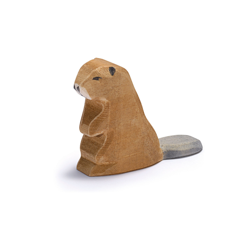 The Ostheimer Beaver - Sitting is a small, wooden figurine featuring a roughly carved, smooth finish. It showcases a beaver sitting upright with a brown body and a gray, flat tail. Handcrafted in the classic Ostheimer style, it has minimal details for a simple and rustic look. This charming piece is perfect for imaginative play against its white background.