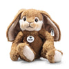 The Steiff Bommel Dangling Rabbit is a plush brown bunny with floppy ears, white accents on its cheeks and feet, and a signature Steiff tag—an adorable, huggable companion that sits upright against a white background.