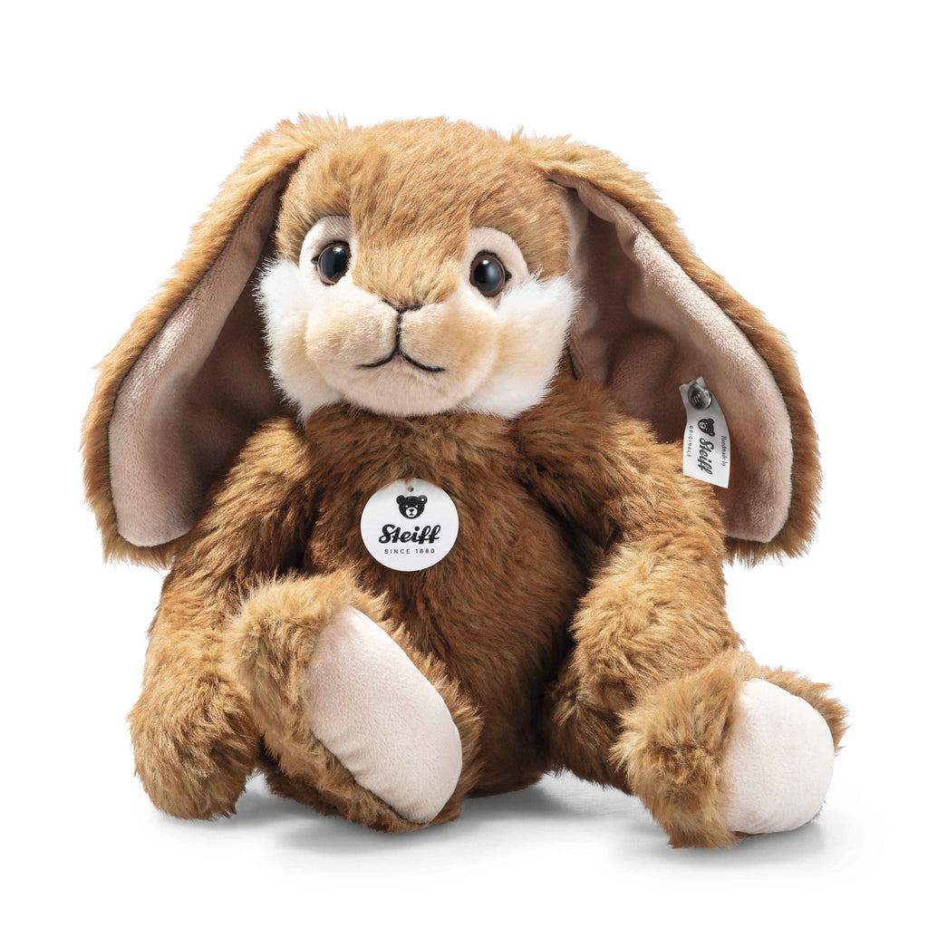 The Steiff Bommel Dangling Rabbit is a plush brown bunny with floppy ears, white accents on its cheeks and feet, and a signature Steiff tag—an adorable, huggable companion that sits upright against a white background.