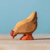 The Bumbu Handmade Wooden Brown Hen is a small, handcrafted figurine made from sustainable Romanian wood, featuring a natural finish with red beak and feet, appearing to peck at the ground.