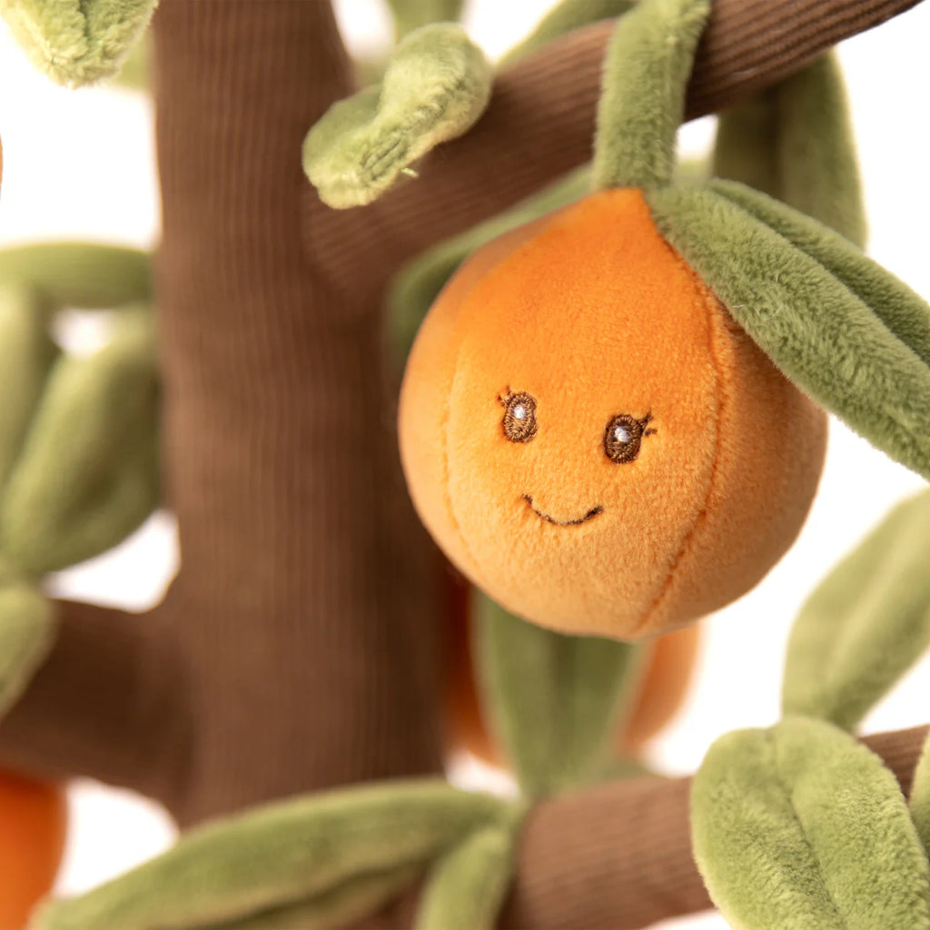 The Bukowski - Orange Tree is a plush toy featuring a smiling orange with embroidered eyes, attached to a soft fabric tree with green leaves and a brown trunk—perfect for cuddly, imaginative play.