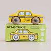 A yellow wooden taxi toy, named No. 39 GT245 Trixie and made in England, sits atop its green box packaging, which displays an illustration of the New York taxi along with the text “No. 39 GT245 Trixie | Made in England” and “Limited Edition.” Black and white checks decorate the side of the toy, making it ideal for imaginative play.