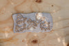 Five insect-shaped cookie cutters from the Insect Cutter Set - Eco Playdough Tool are pressed into gray clay on a light wooden surface, displaying a bee, dragonfly, butterfly, grasshopper, and ladybug. This sensory play set features eco-friendly playdough tools designed as insect-themed cutters to inspire imaginative and nature-focused creativity.